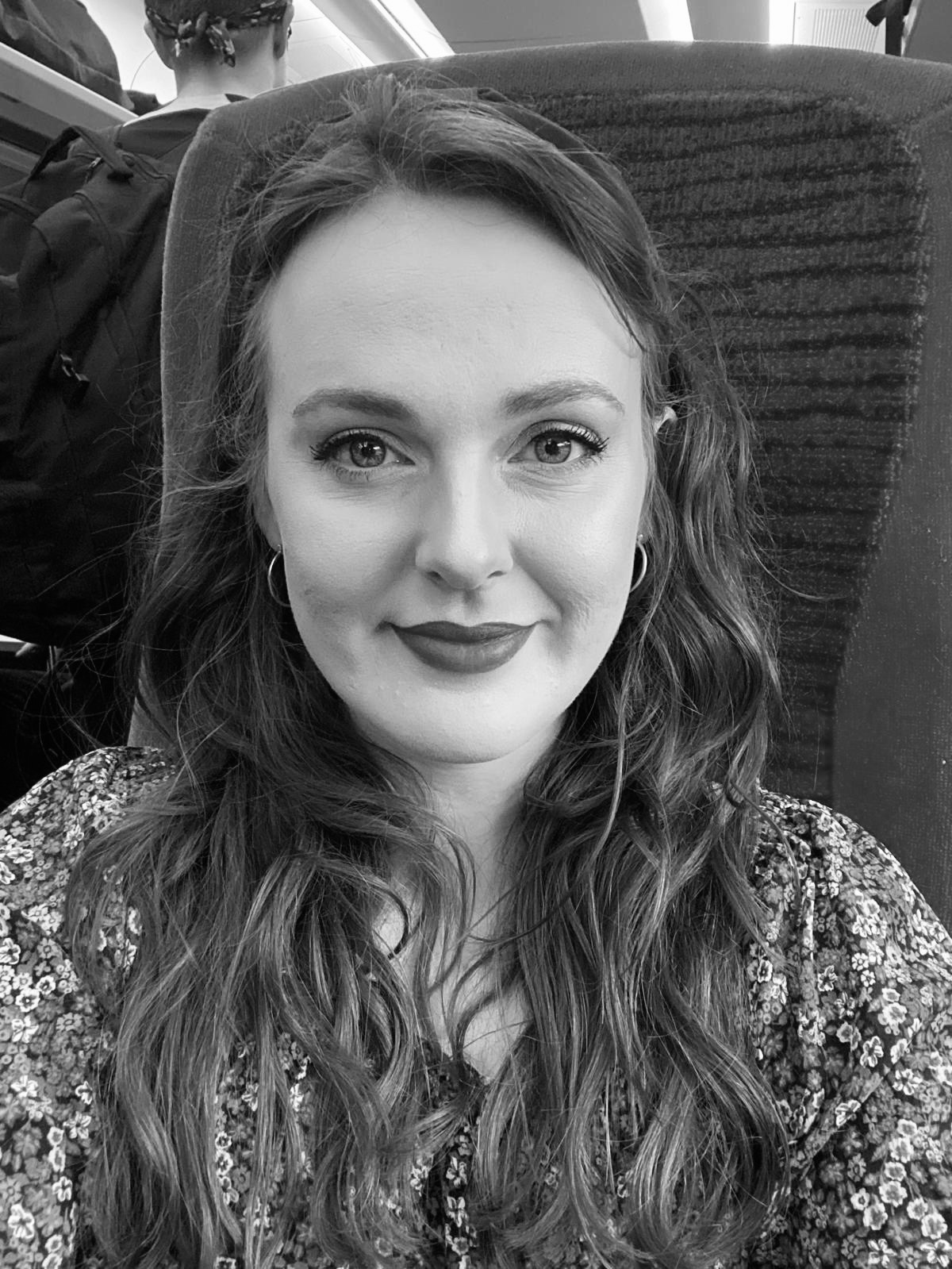 a black and white image of a smiling girl with red lipstick and long dark hair